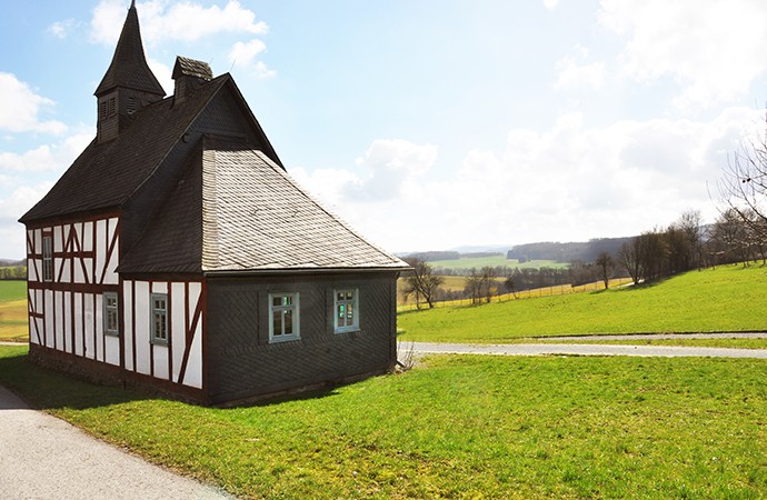 Die Kapellenschule Werthenbach. Dahinter eine Wiese und weite Felder