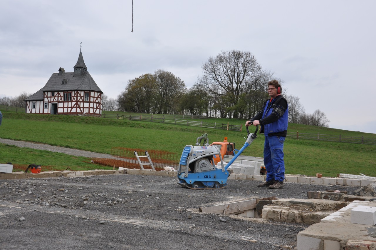 Zu sehen ist wie ein Gebäuderestaurator mit einer Rüttelmaschine das Füllmaterial verfestigt.