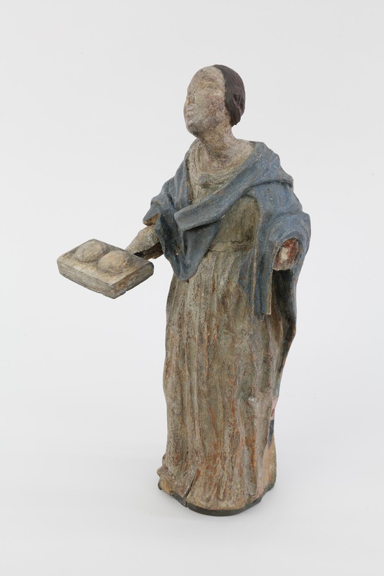 Hölzerne Figur der heiligen Agatha im weißen Gewand mit blauem Umhang.