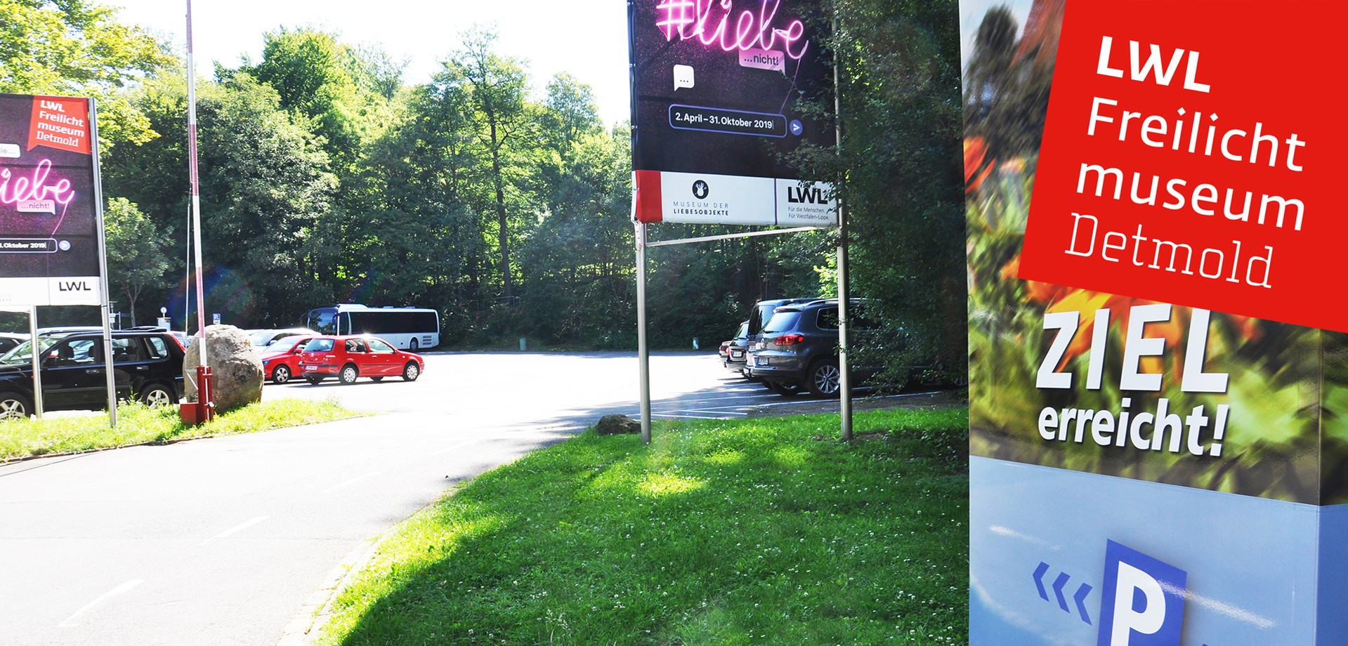 Einen Ausschnitt von unserem Parkplatz.. Rechts ist ein Schild mit der Aufschrift "Ziel erreicht". Geradeaus unser Plakat zur Sonderausstellung Liebe.