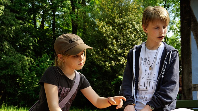 Ein Mädchen und einen Jungen, die sich bei einer Bastelaktion erklären lassen, was sie tun sollen. Ein Mädchen und einen Jungen, die sich bei einer Bastelaktion erklären lassen, was sie tun sollen.