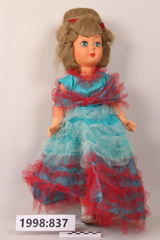 Puppe mit  rot- und türkisfarbenem Kleid.