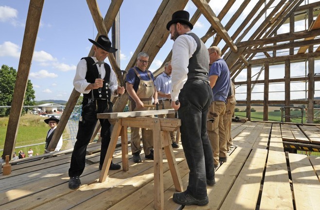 Mit Hämmern wird von den Gebäuderestauratoren auf das Holz geschlagen.