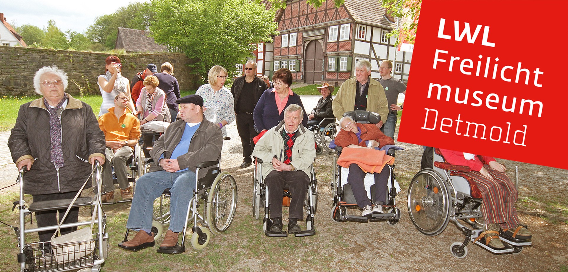 Eine Gruppe von 18 erwachsenen Personen. Einige sind schon etwas älter. Sie benutzen eine Gehhilfe oder sitzen im Rollstuhl.