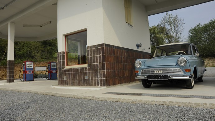 An old car stands next to the museum's historical gas station.