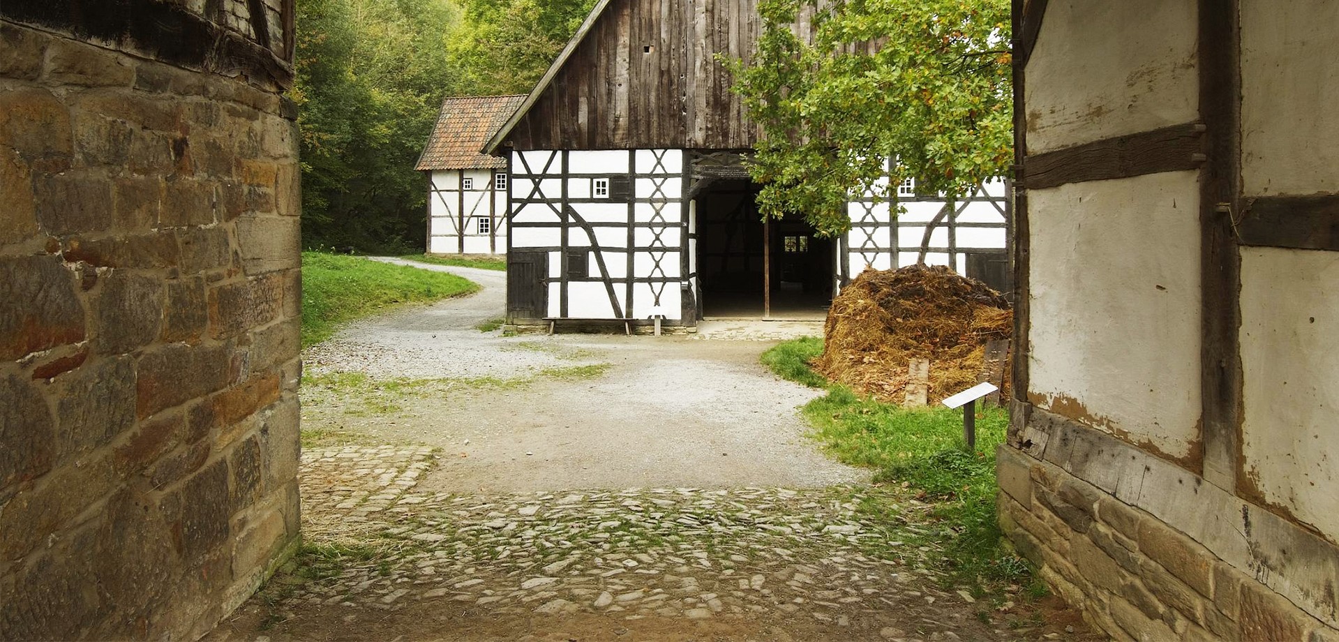 A passage to a farmyard. Straight ahead is a half-timbered house. The passage and the house are a picture of the Gräftenhof.