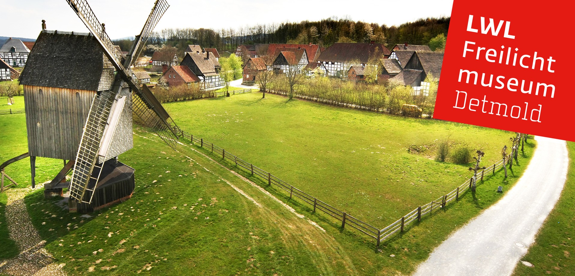 Im Vordergrund eine historische Windmühle. Rechts ist ein Weg zum Paderborner Dorf. Das Paderborner Dorf ist im Hintergrund.