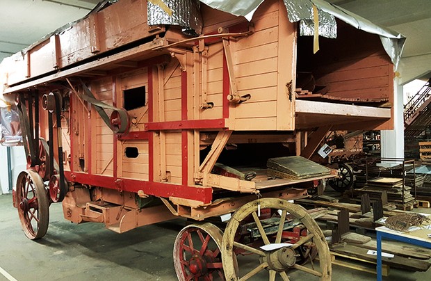 Eine historische Dreschmaschine aus Holz. Sie ähnelt einer Kutsche.