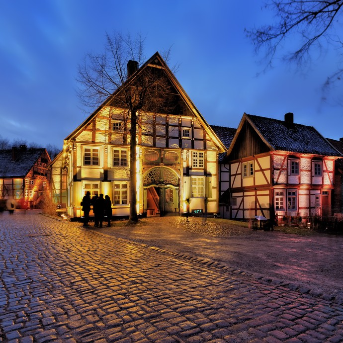 An einem Platz mit Kopfsteinpflaster sind mehrere Fachwerkhäuser, die in farbiges Licht getaucht sind. (Enlarged picture view opens)