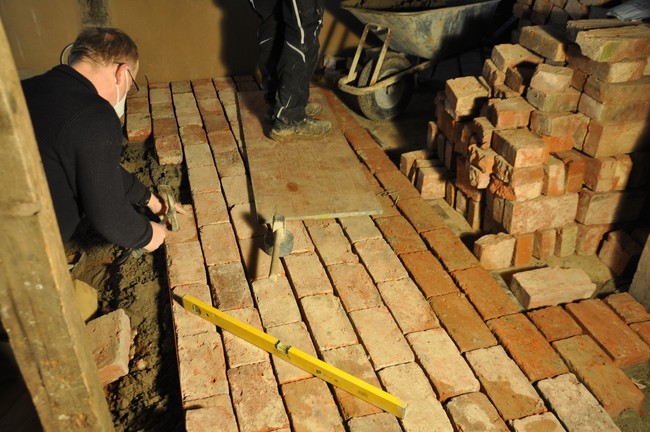 Der Stallanbau hat einen Fußboden aus Ziegelsteinen. Diese werden in Mörtel gelegt. Gut, dass wir für diesen Fußbodenaufbau genügend Höhe haben.