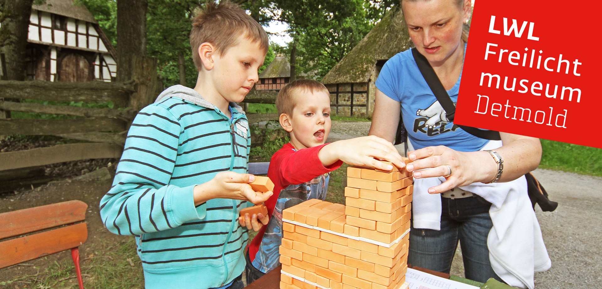 Ein Mädchen und zwei Jungs, die sich bei einer Bastelaktion mit Ton. Sie bauen mit Steinen aus Ton einen Turm.